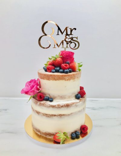 Semi-naked two tier cake with berries and fresh flowers