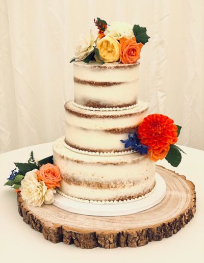 Three tier semi-naked wedding cake decorated using fresh flowers